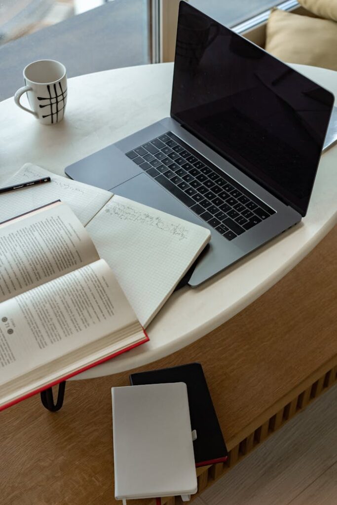 pexels-photo-7583935 A cozy indoor workspace featuring a laptop, open book, notepad, and coffee, perfect for studying or remote work.